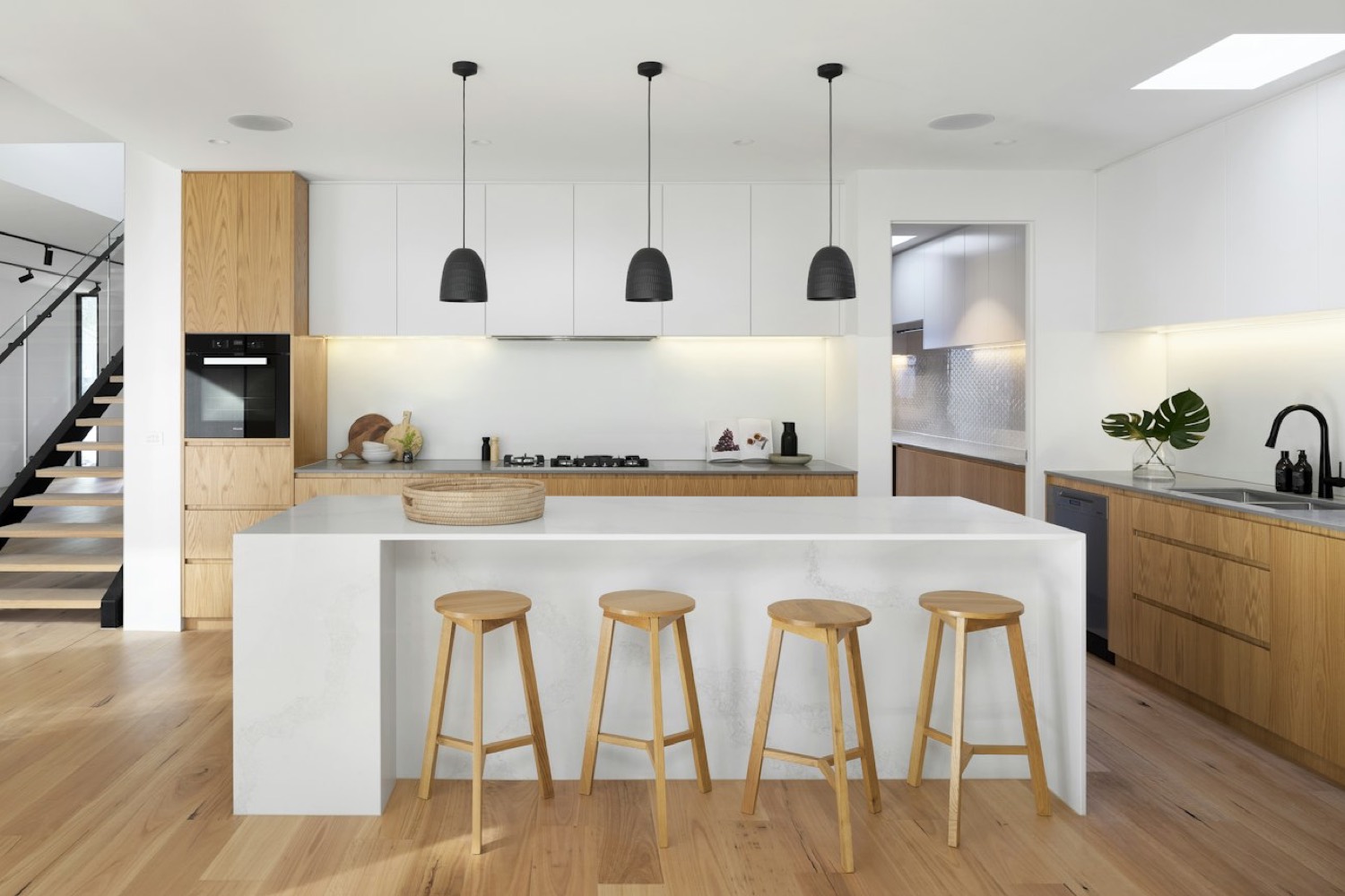 Minimal kitchen with a stone island, oak joinery and black pendant lights